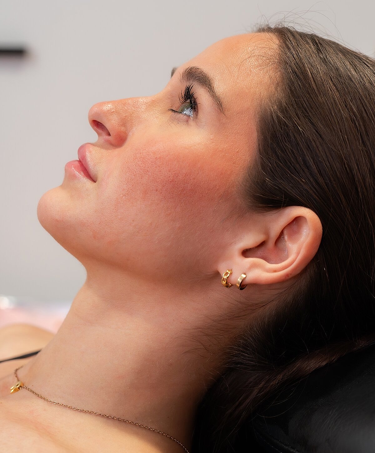 Woman examining lips in mirror at clinic.