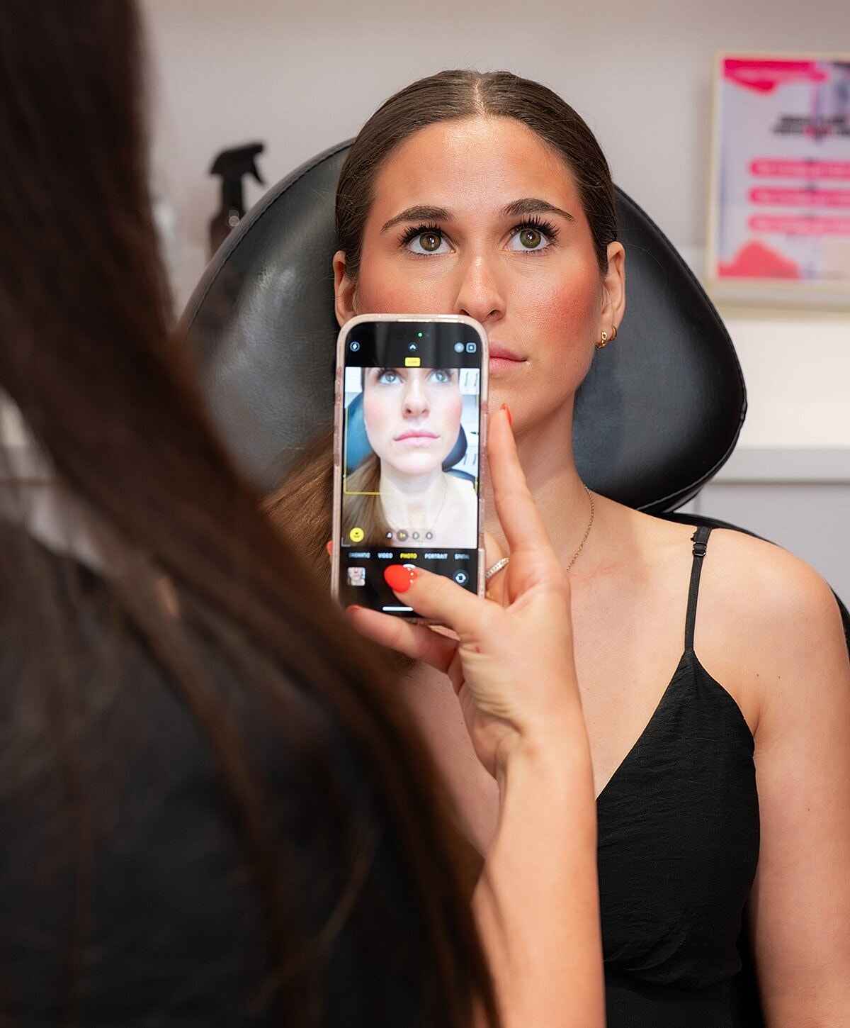 Woman examining lips in mirror at clinic.