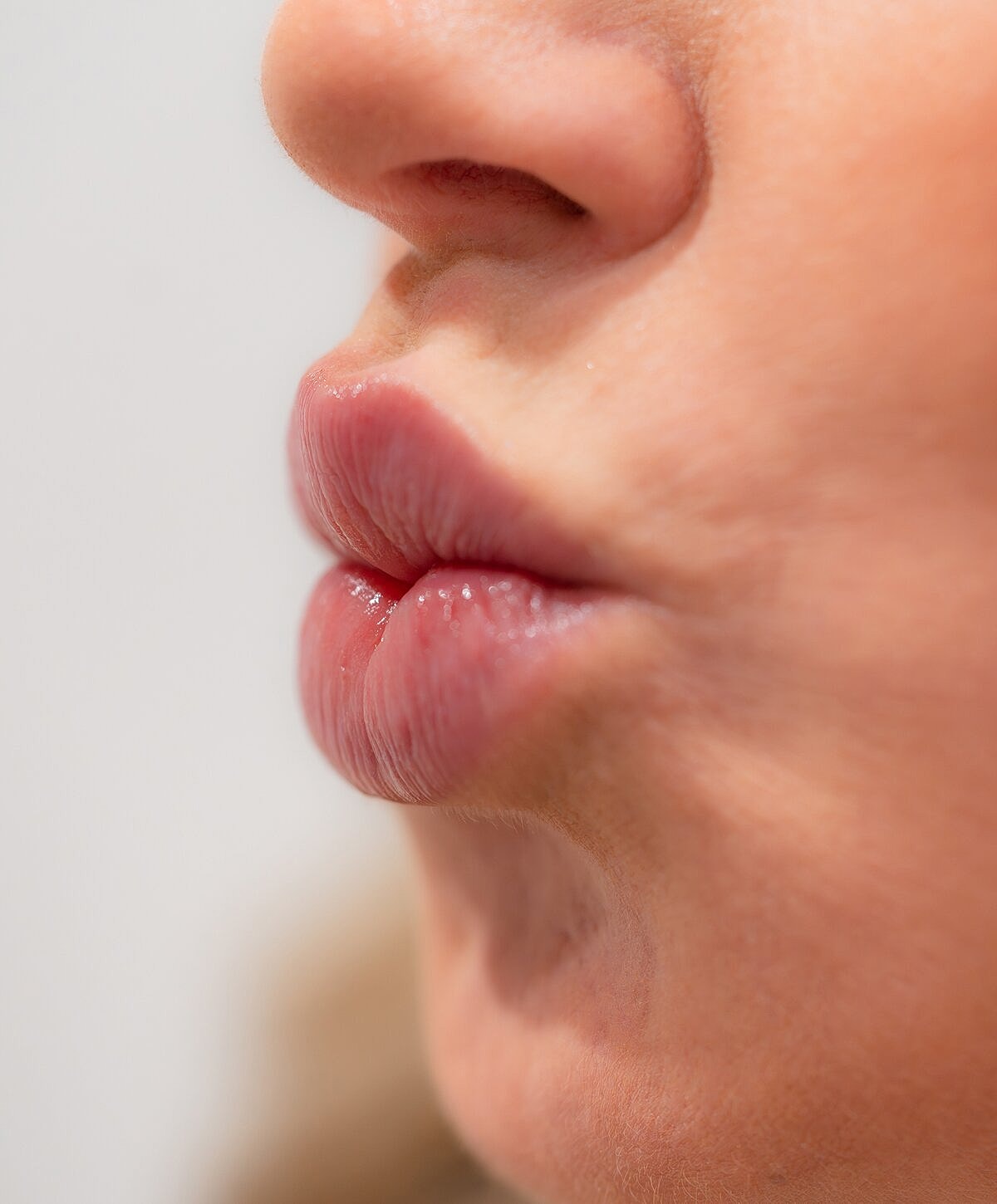 Woman examining lips in mirror at clinic.