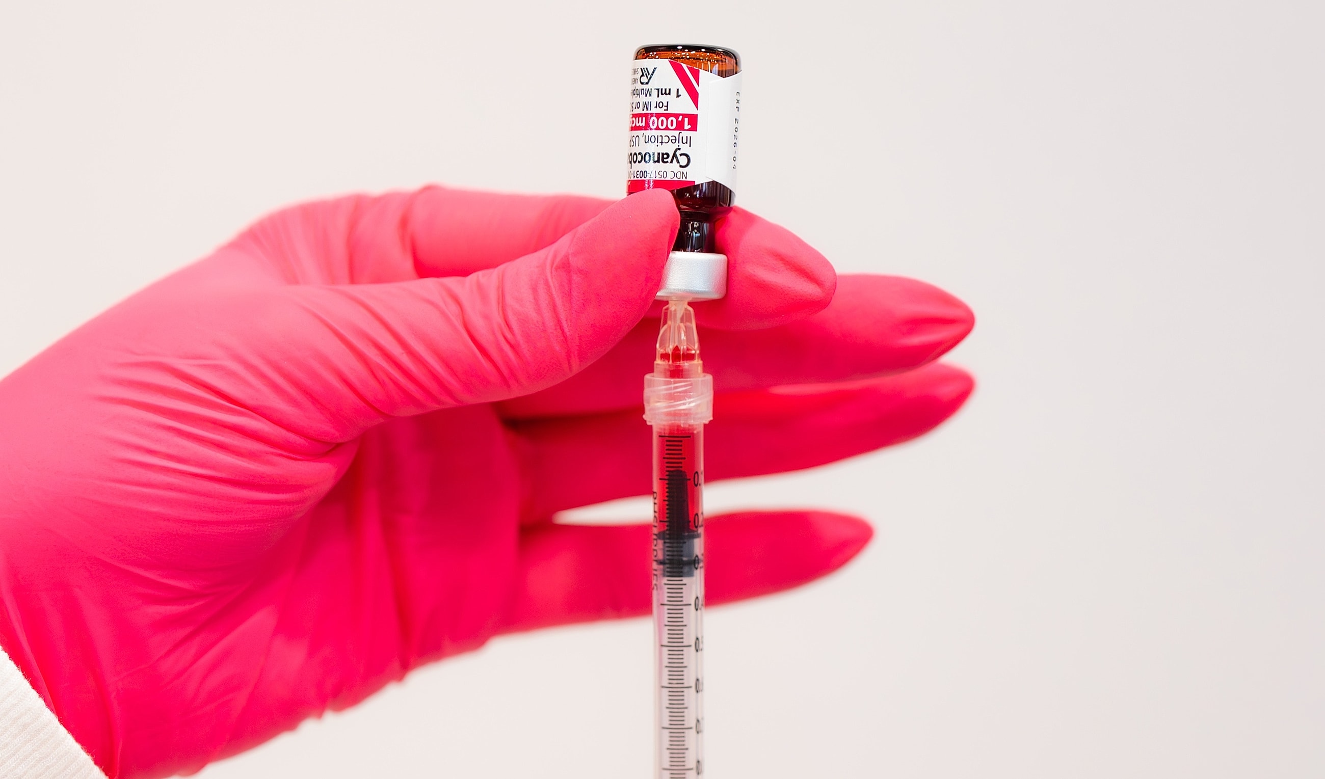 Hand holding syringe with vaccine vial.