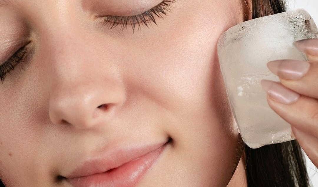 Woman applying ice to her face for skincare.