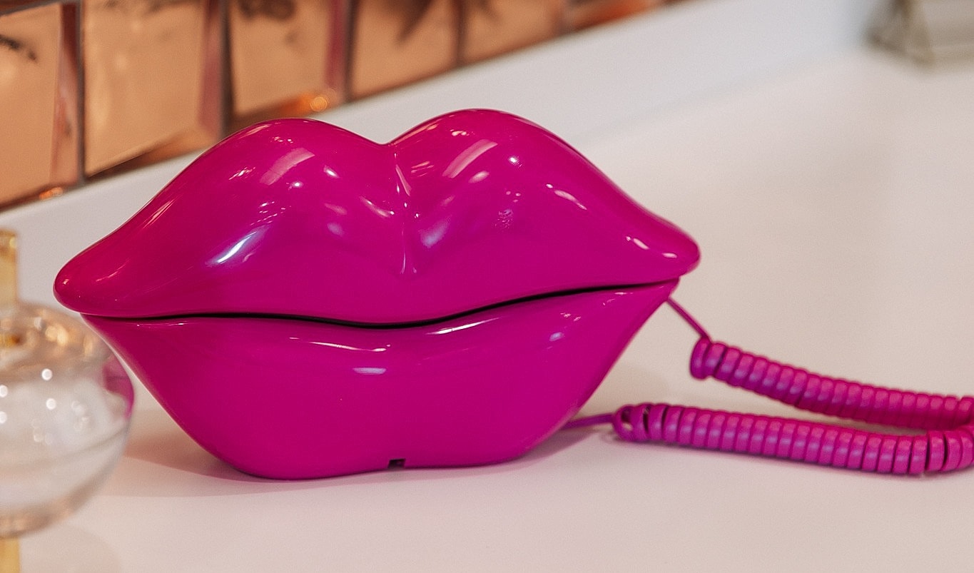 Pink lips-shaped phone on a white surface.