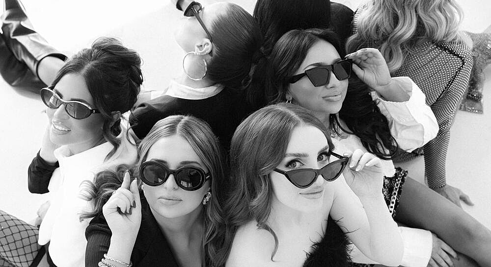 Group of women wearing sunglasses posing together.