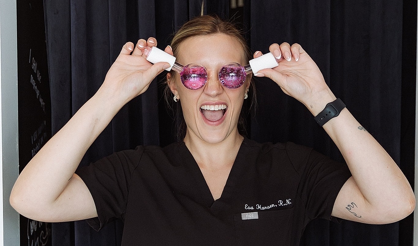 Woman wearing pink sunglasses and smiling joyfully.