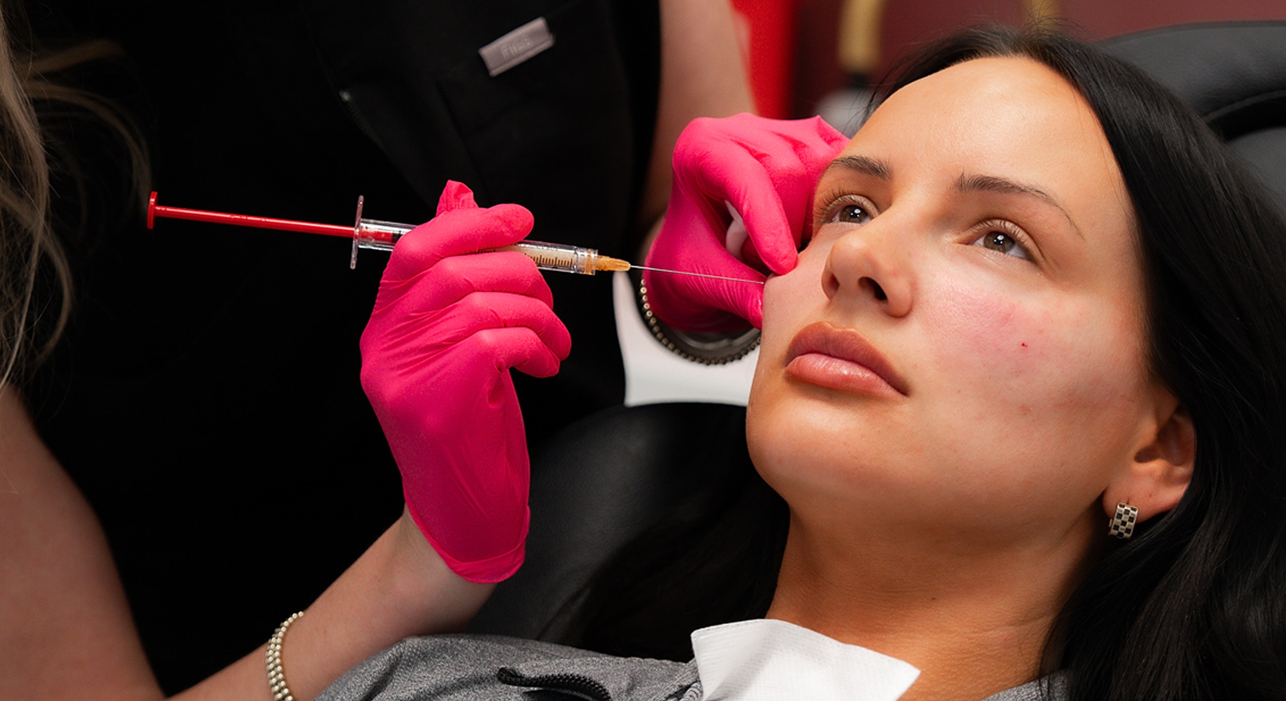 Woman receiving cosmetic treatment with injector tool.