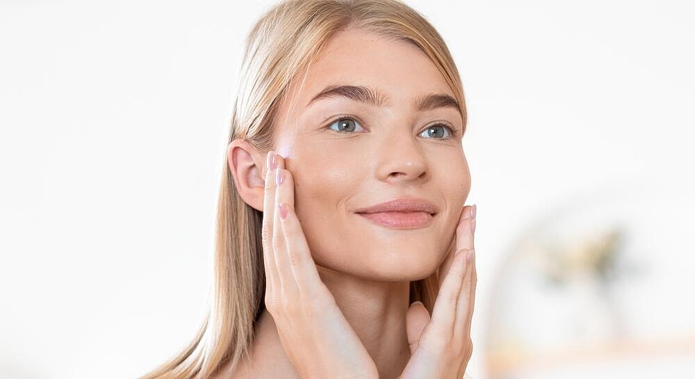Woman applying skincare product on her face.
