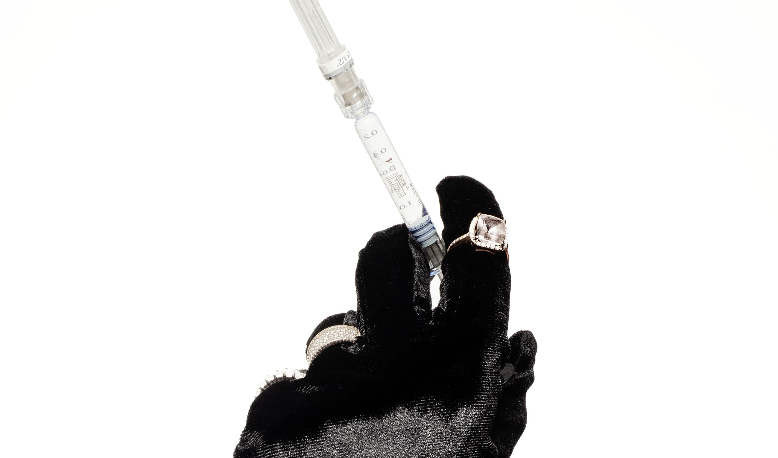 Gloved hand holding a syringe with elegance.