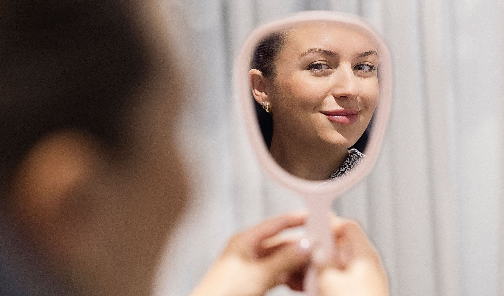 Woman looking in a mirror, smiling.